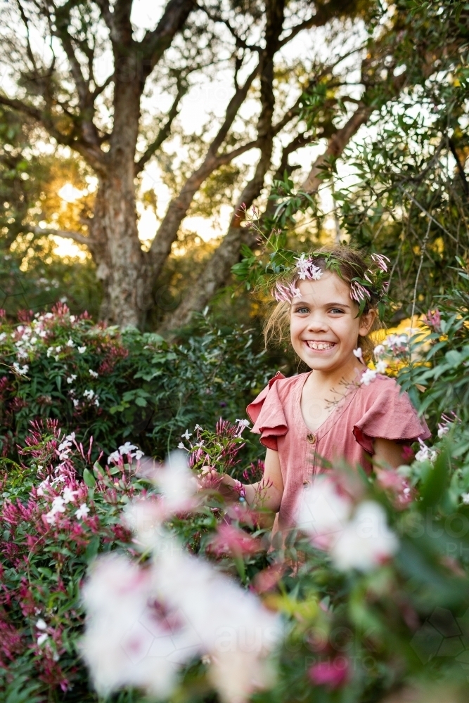 Smiling preteen girl standing amongst spring Jasmine flowers in garden in country - Australian Stock Image