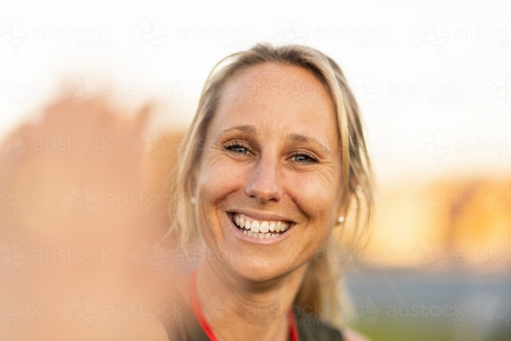 smiling tanned blonde woman outdoors with foreground blur - Australian Stock Image