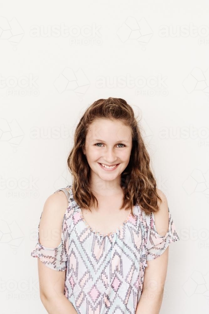 smiling teen girl against a blank wall - Australian Stock Image