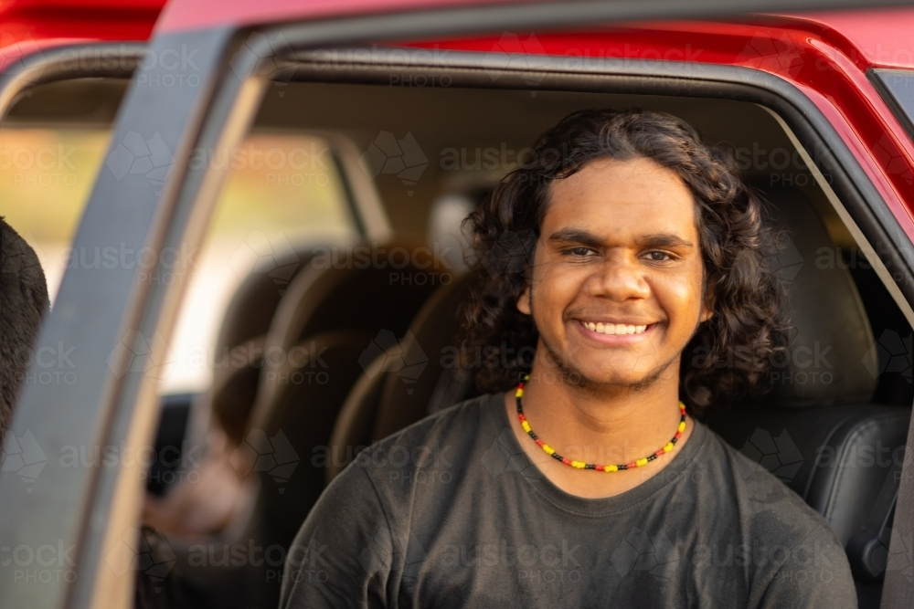 Smiling teenage boy from back seat with car door open - Australian Stock Image