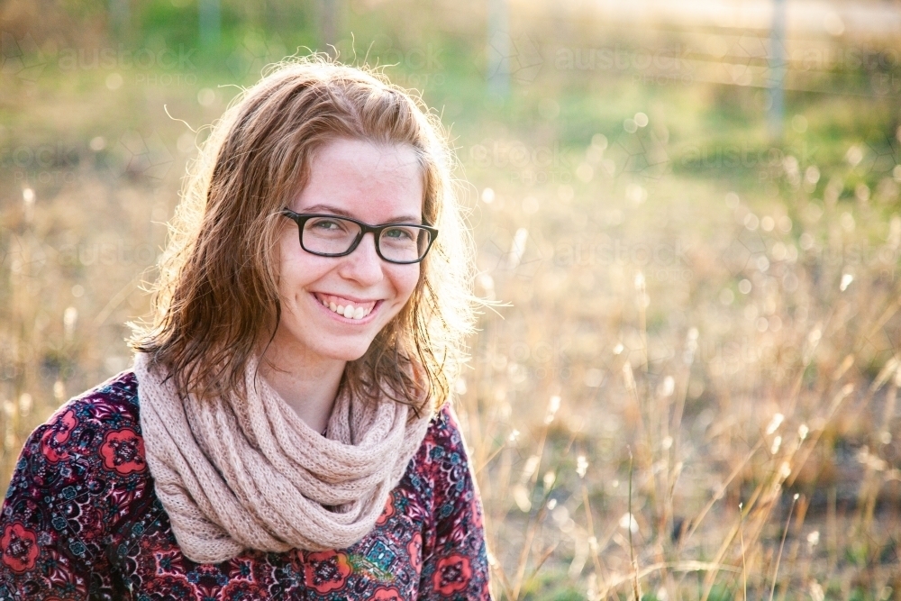 Smiling teenager with scarf outside in natural surroundings - Australian Stock Image