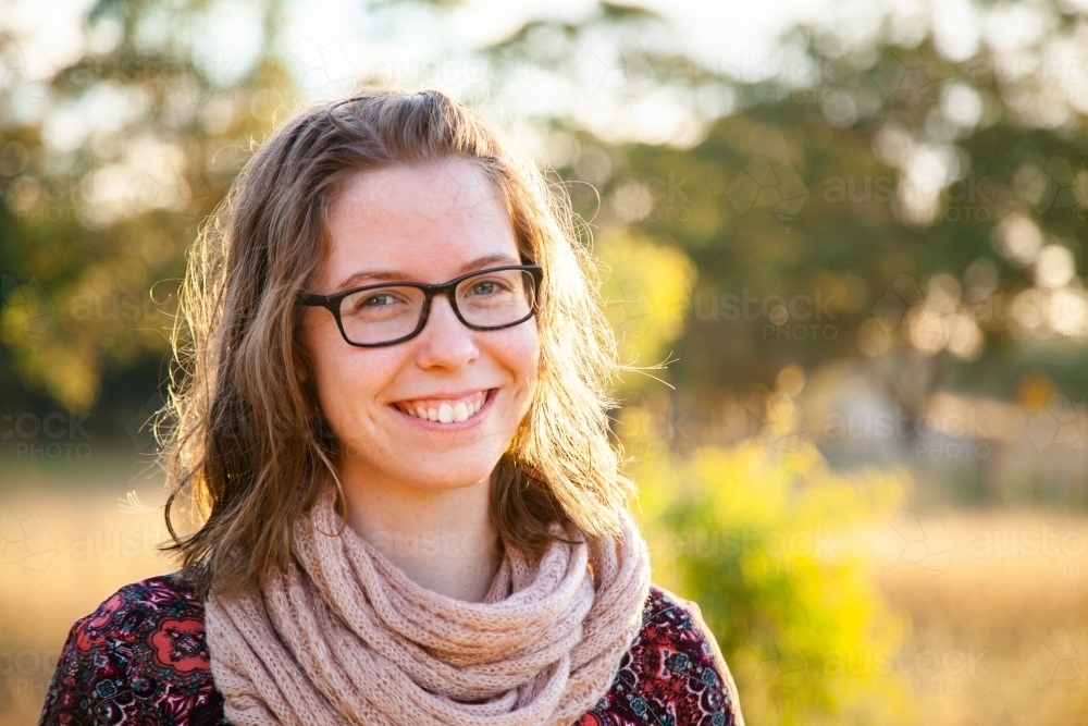 Smiling teenager with scarf outside in natural surroundings - Australian Stock Image