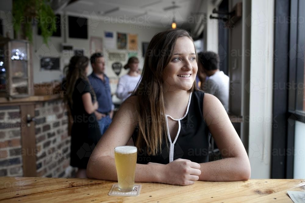 Smiling woman having a drink at local craft beer bar - Australian Stock Image