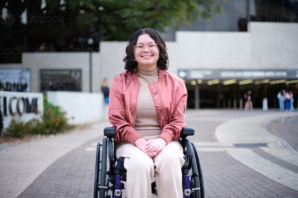 Smiling woman with a disability sitting in a wheelchair outside - Australian Stock Image