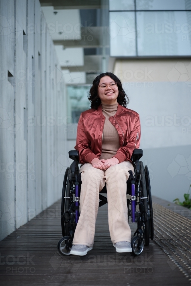 Smiling woman with a disability sitting in a wheelchair outside - Australian Stock Image