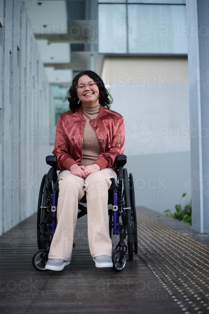 Smiling woman with a disability sitting in a wheelchair outside - Australian Stock Image