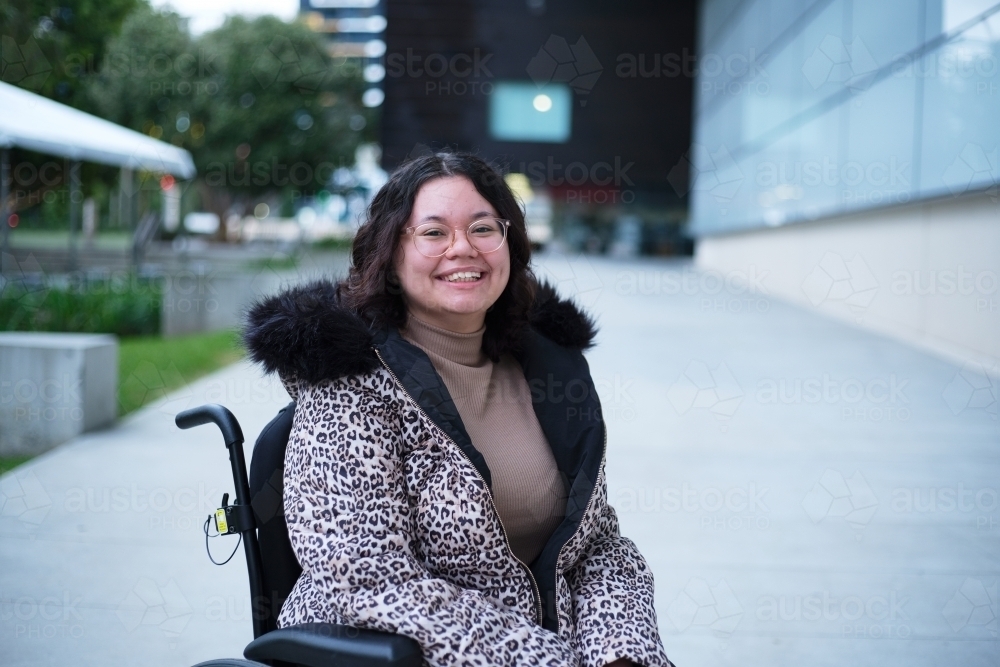Smiling woman with a disability sitting in a wheelchair outside - Australian Stock Image