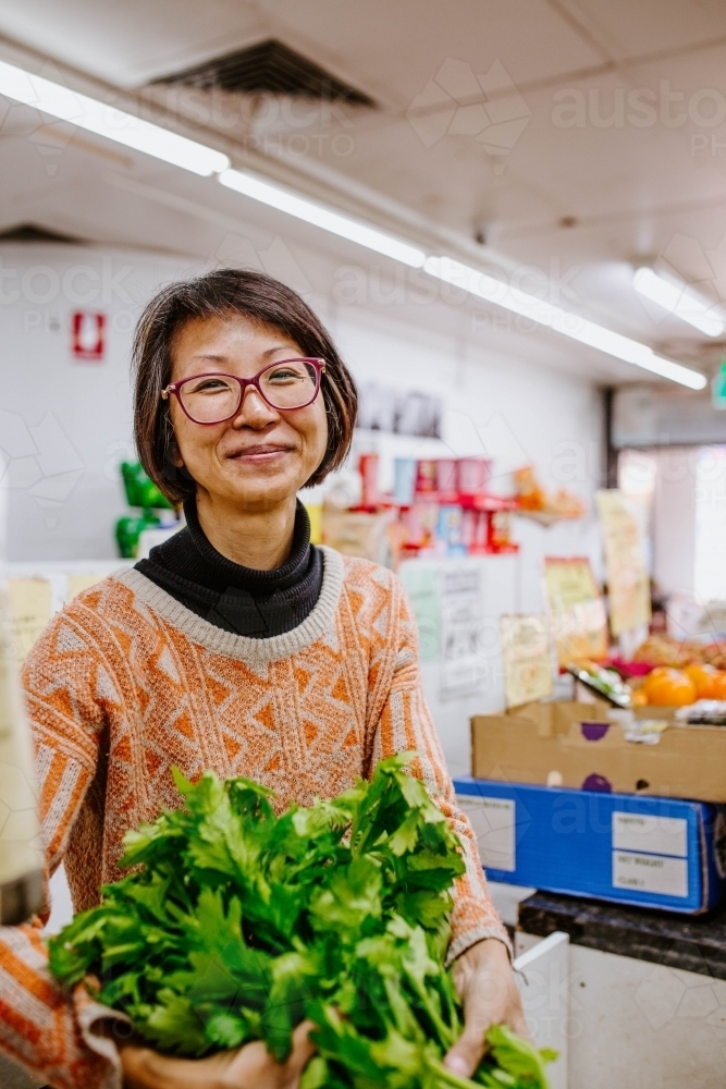 Smiling woman with glasses working in supermarket - Australian Stock Image