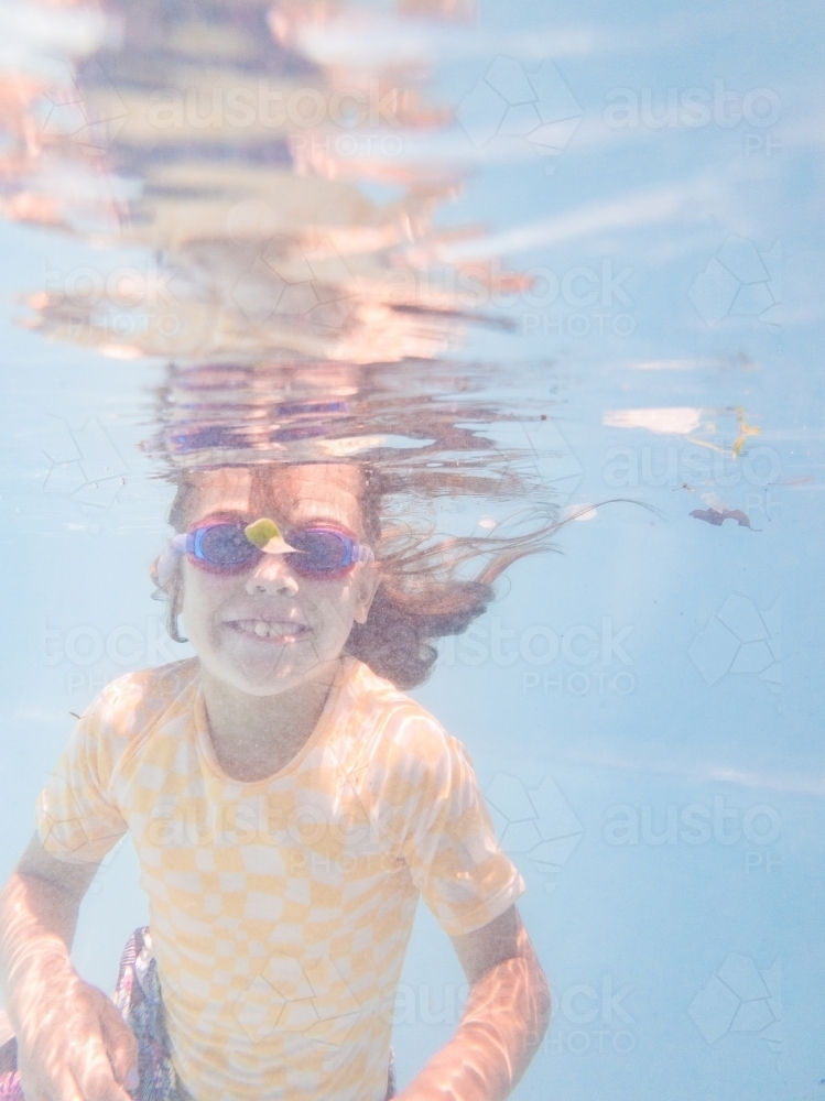 Image of Smiling young Australian girl swimming in pool with goggles on ...