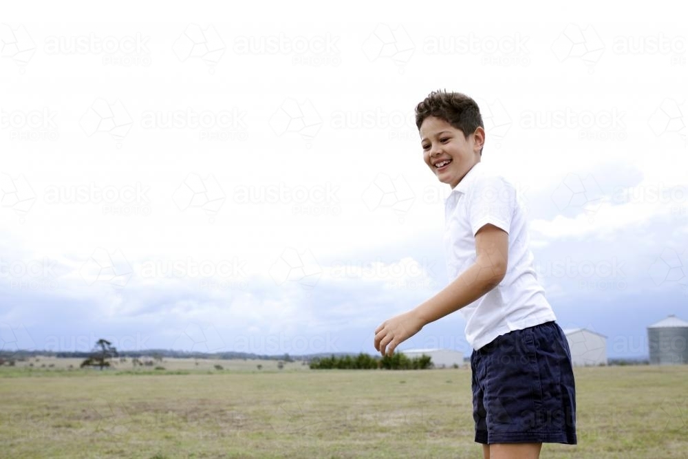 Smiling young boy in sport uniform standing in a farm paddock - Australian Stock Image