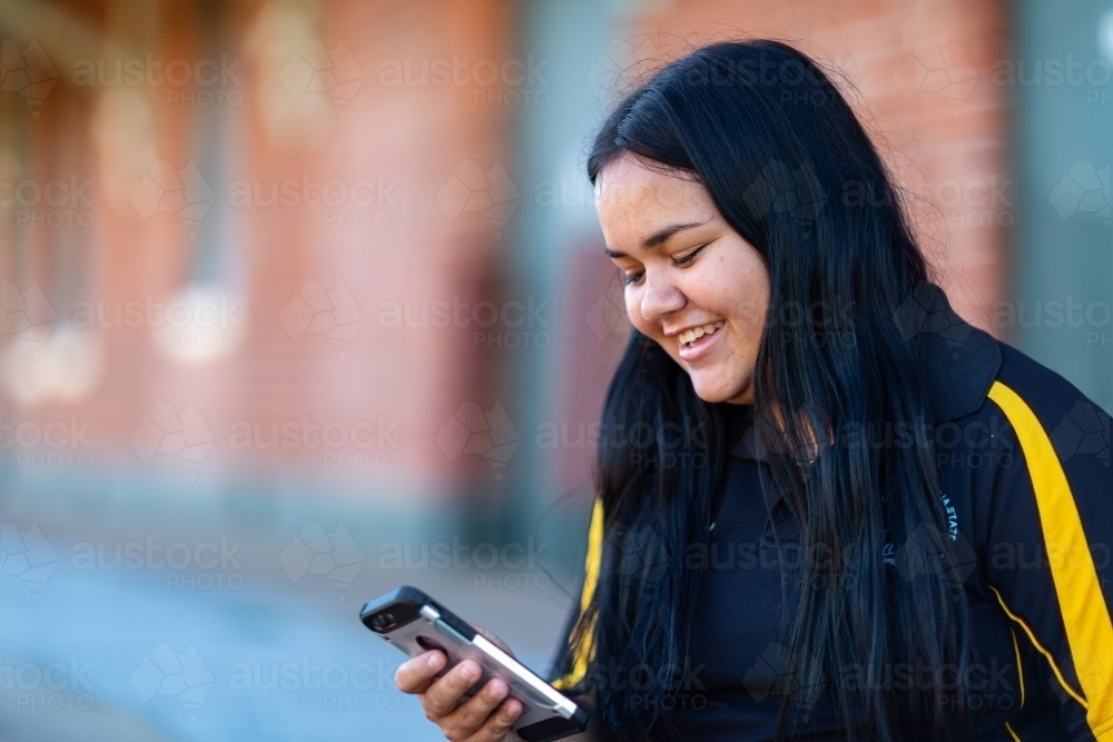 smiling young lady looking at smartphone - Australian Stock Image