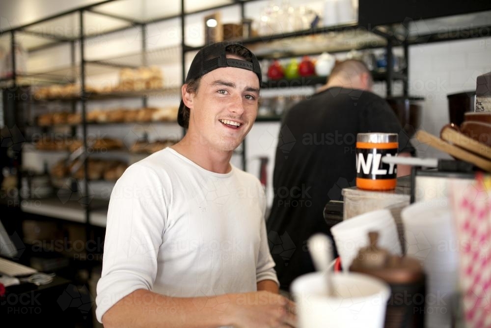 Smiling young man at work at cafe - Australian Stock Image