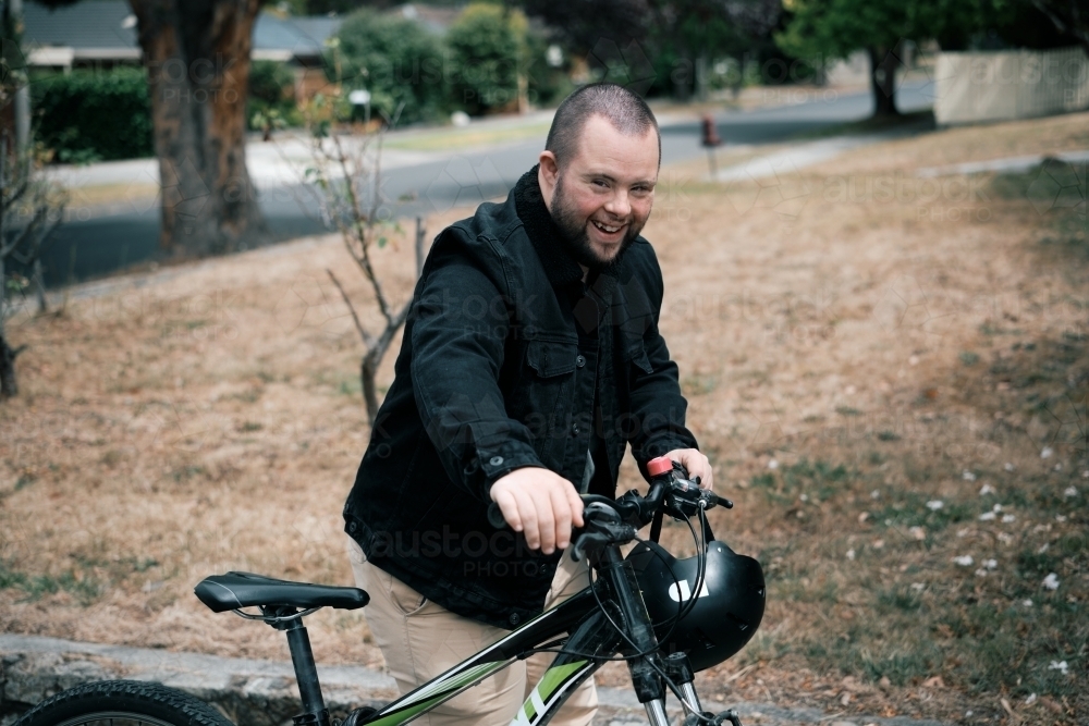 Smiling Young Man with Down Syndrome Walking Bike - Australian Stock Image