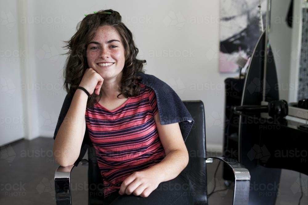 Smiling young woman waiting at a hairdressing salon - Australian Stock Image