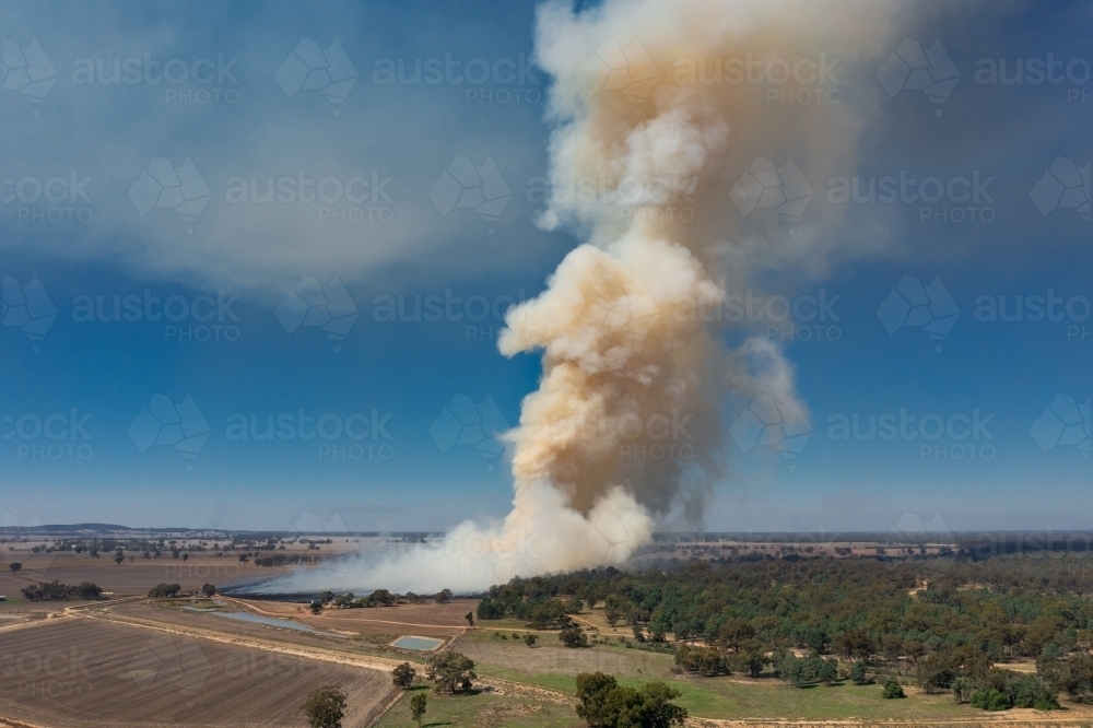 Smoke billowing into the air from a bush fire over dry farmland - Australian Stock Image