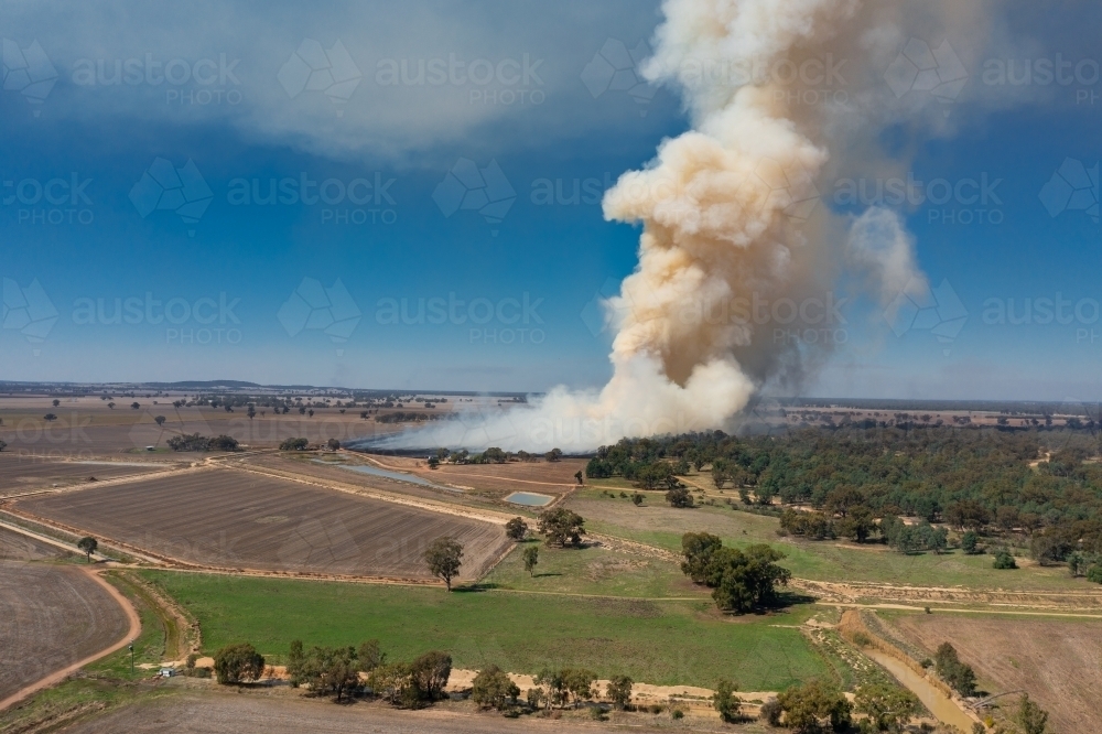 Smoke billowing into the air from a bush fire over dry farmland - Australian Stock Image