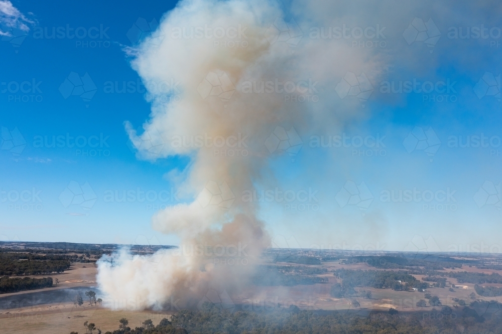 Image of smoke billowing up over bush and farmland - Austockphoto