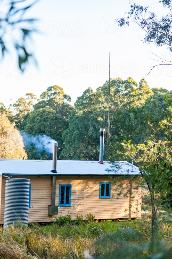Smoke coming from chimney in cabin in clearing - Australian Stock Image