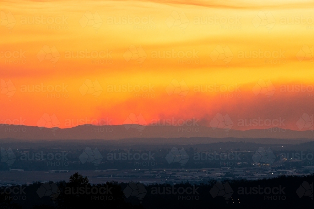 Smoke from fires on the ranges in an orange sunset - Australian Stock Image