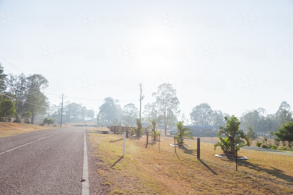 Smoke haze over road and properties at the edge of a town - Australian Stock Image