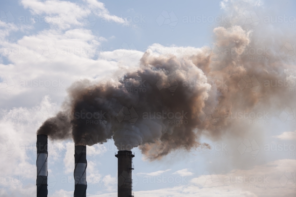 Smoke pouring from smokestacks at a rural sugar refinery - Australian Stock Image