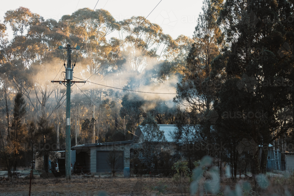 Smoke rising from chimney of farmhouse on cold winter morning - Australian Stock Image