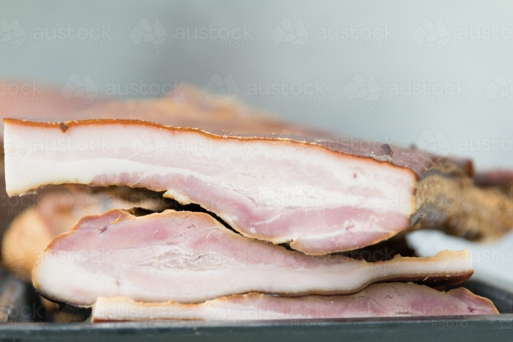 Smoked unsliced bacon on a tray in butchers shop - Australian Stock Image