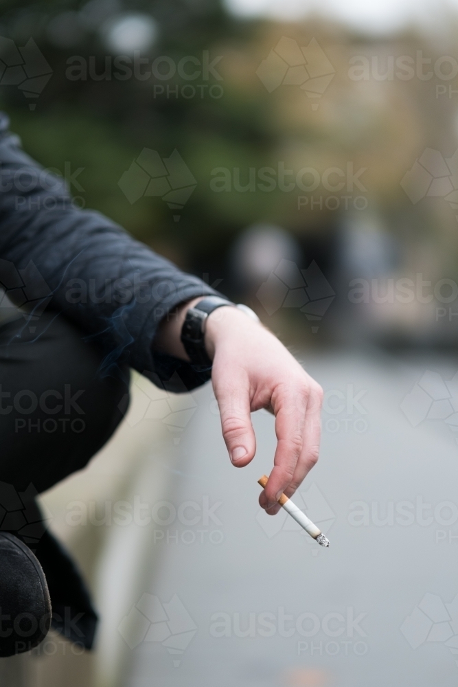 Image of Smoker holding a cigarette at outdoor smoking Image of Smoker holding a cigarette at outdoor smoking