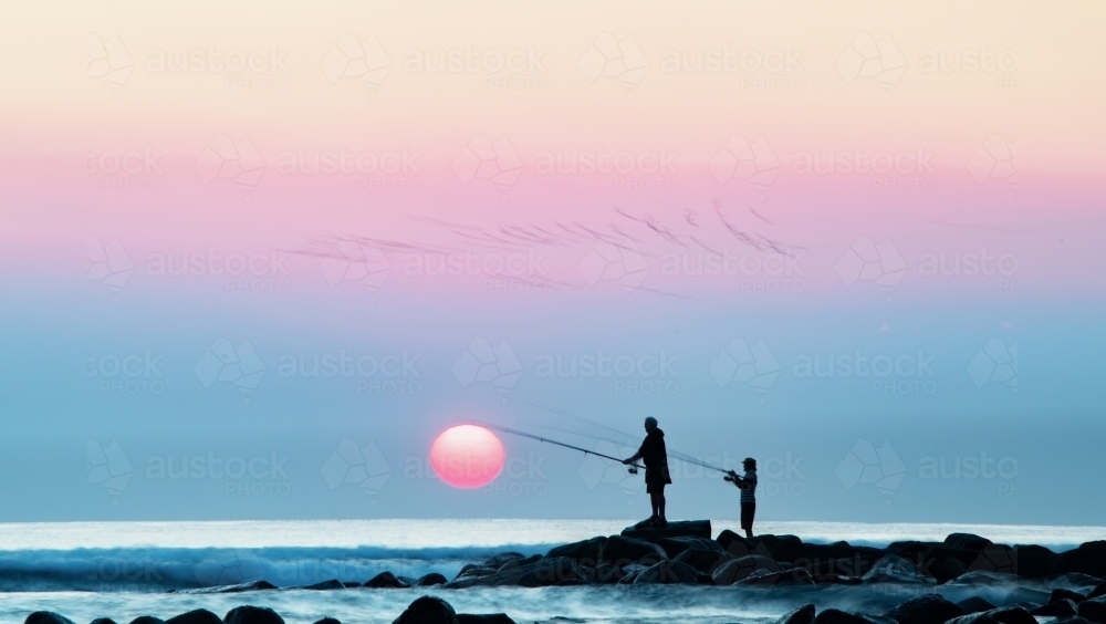 Smokey hazy over the coast while fishermen fish next to rising sun. : Austockphoto Smokey hazy over the coast while fishermen fish next to rising sun. - Australian Stock Image