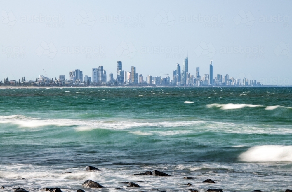 Smooth waves over the ocean with the Gold Coast skyline in the distance - Australian Stock Image