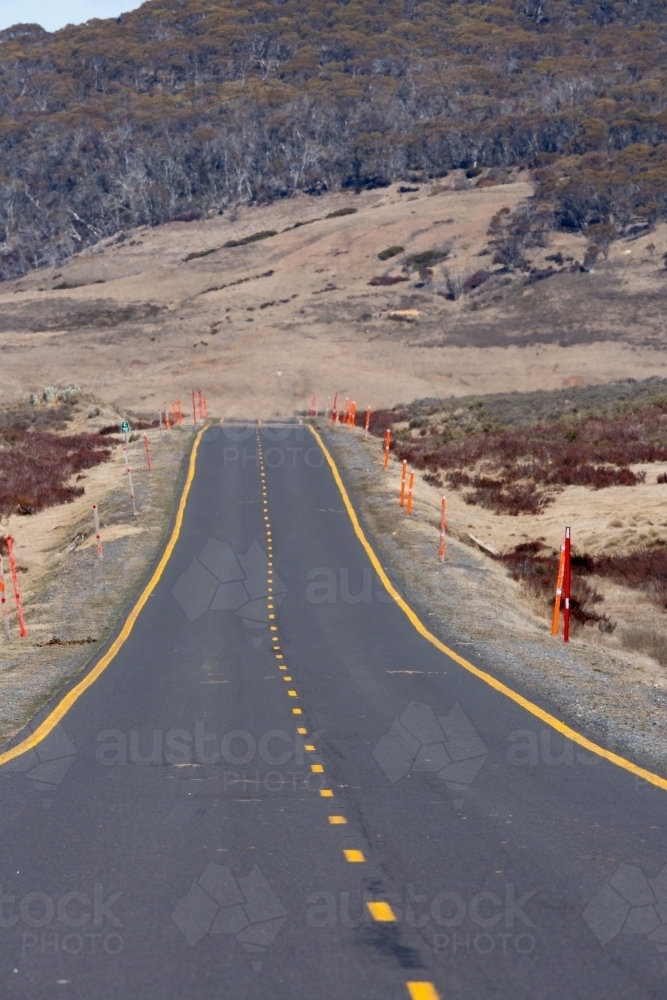 Snowy Mountains Highway, an alpine road with yellow road markings and orange snow guides - Australian Stock Image