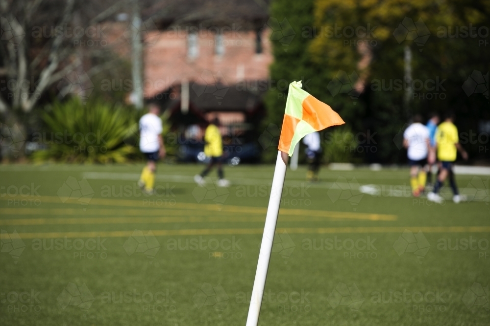Soccer players on a field with flag in foreground - Australian Stock Image