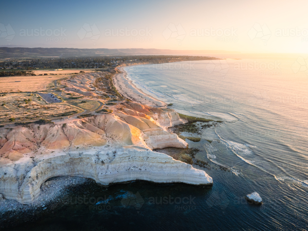Soft golden light spills across the layered cliffs and coastline of Maslin Beach, South Australia - Australian Stock Image