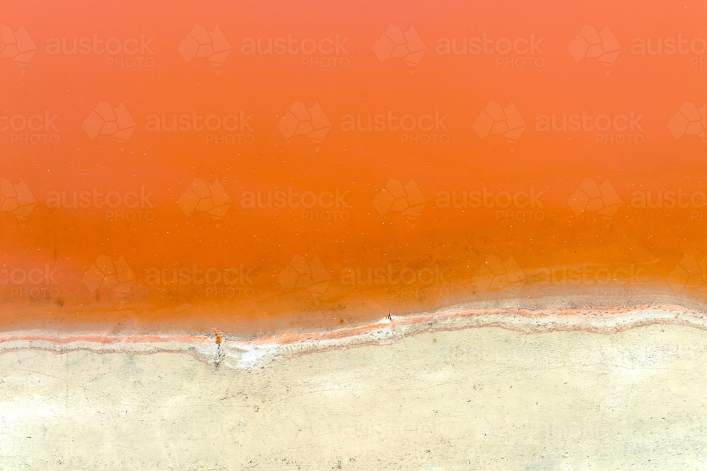 Soft orange salt lake meeting pale cracked shoreline - Australian Stock Image