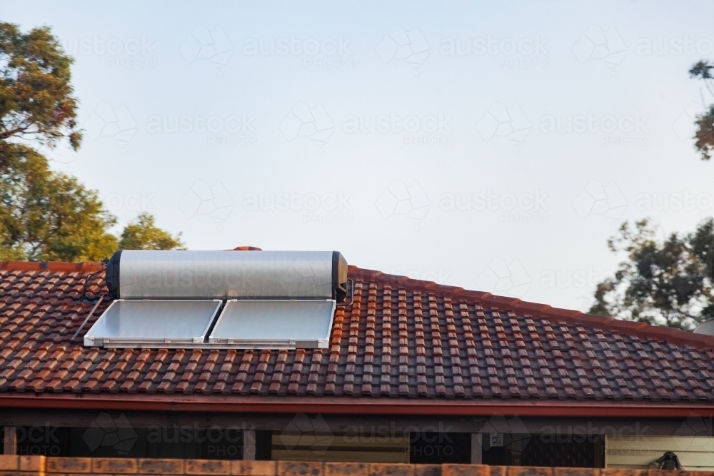 Solar panel and hot water heater on tilled roof of home - Australian Stock Image