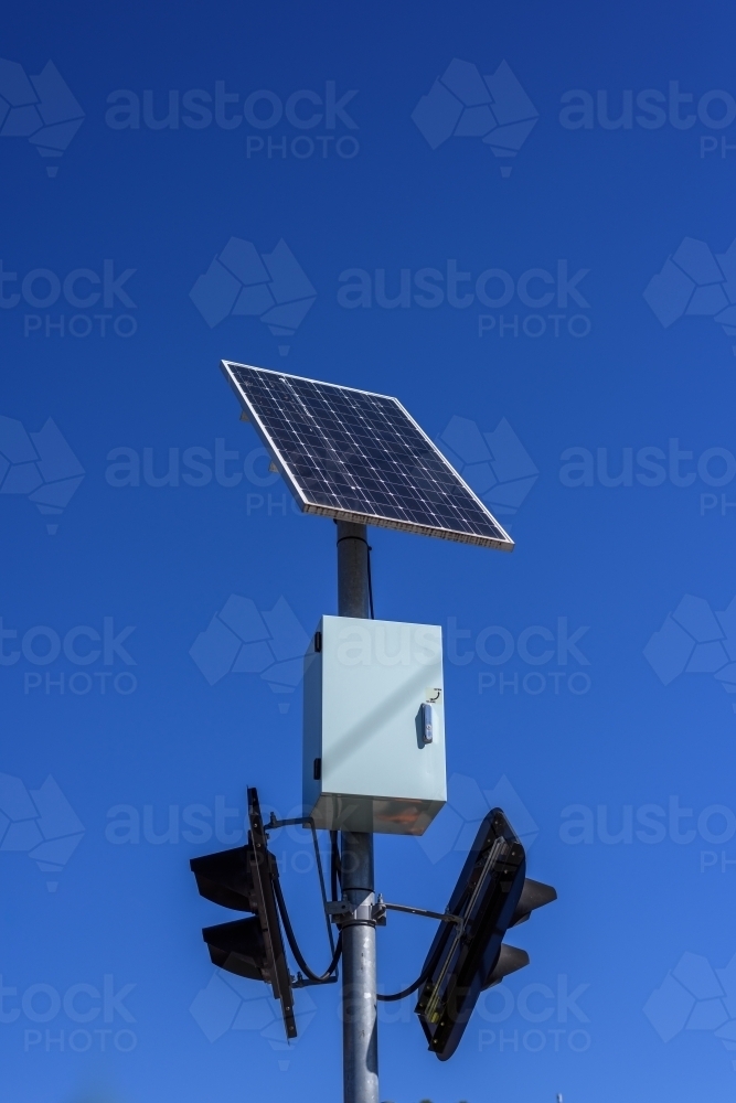 Solar panel powered traffic light against blue sky background, clean energy in use - Australian Stock Image