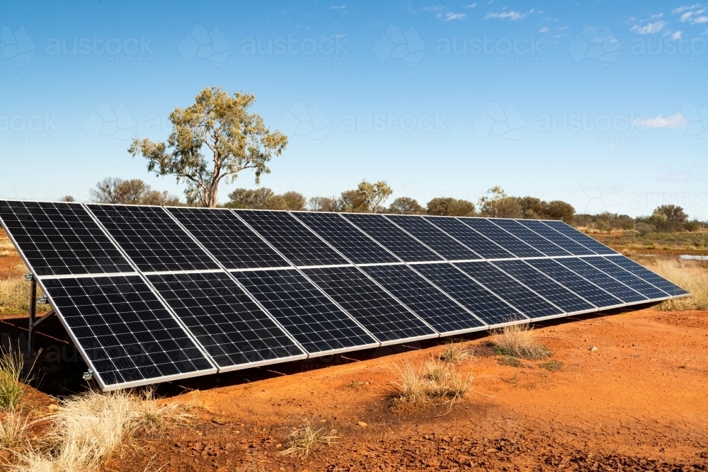 Solar Panels in desert region with cracked orange mud in foreground - Australian Stock Image