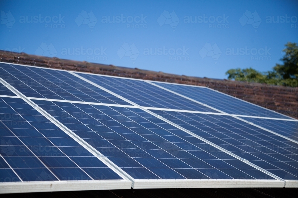 Solar panels installed on roof under blue sky - Australian Stock Image