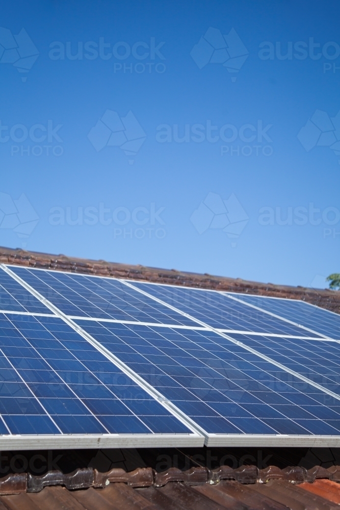 Solar panels installed on roof under blue sky - Australian Stock Image