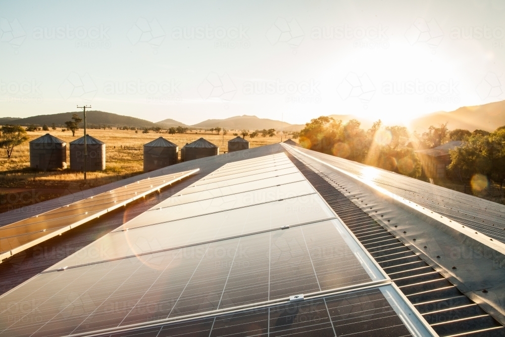 Solar panels on a shed roof generating energy with sunlight lens flare - Australian Stock Image