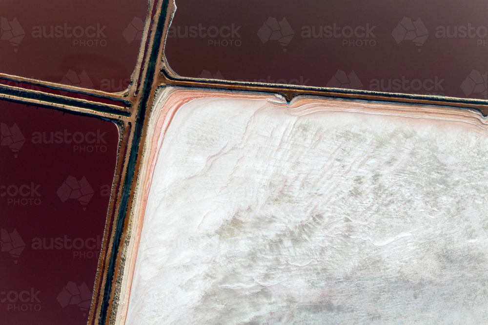 Solitary salt pan viewed from above with bold contrasts of red water and white crust. - Australian Stock Image
