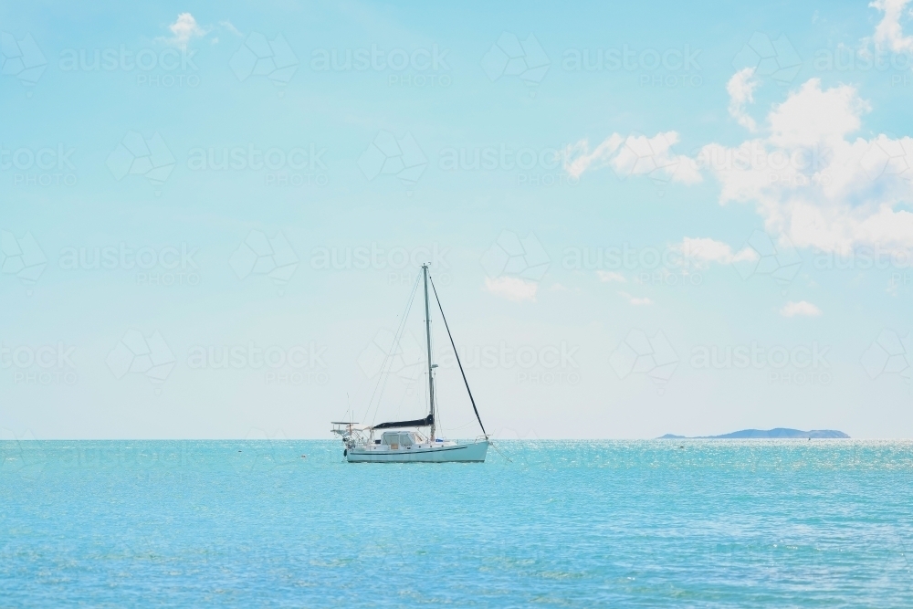 Solo yacht on calm ocean water in the Whitsundays - Australian Stock Image