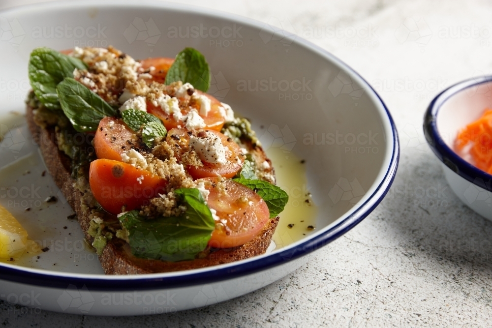 Sourdough with avocado, tomatoes, feta and herbs served with oil and lemon - Australian Stock Image