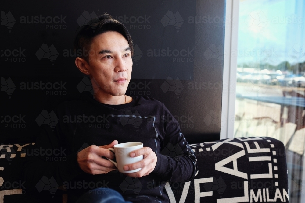 Southeast Asian multicultural man drinking coffee - Australian Stock Image