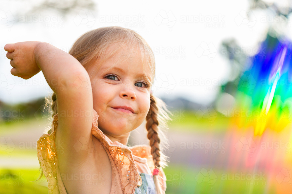Sparkling rainbow light beside happy young Aussie child outside in sunshine - Australian Stock Image