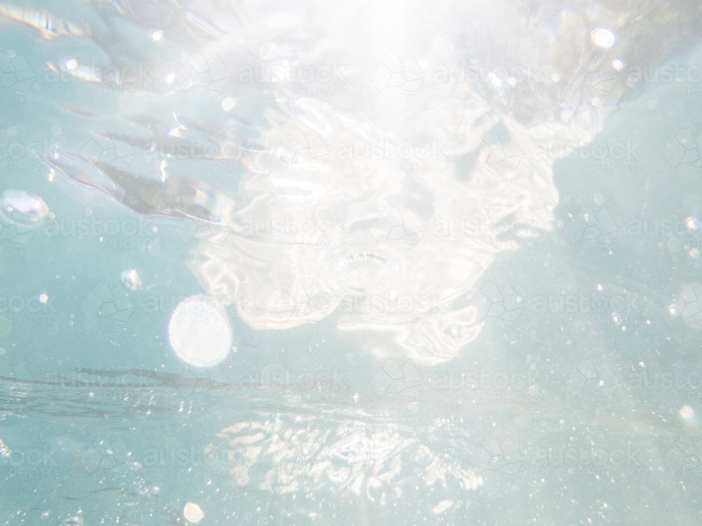 Sparkling sunlight seen through clear blue water of pool with bubbles - Australian Stock Image