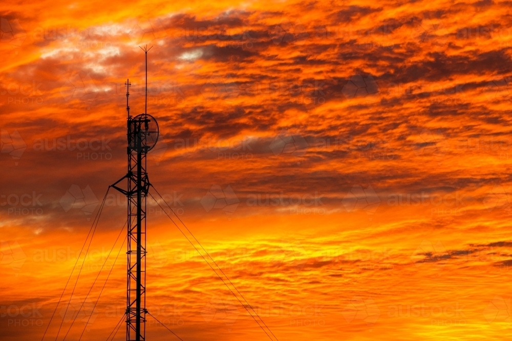 Spectacular orange sunset sky with communications tower silhouette. - Australian Stock Image