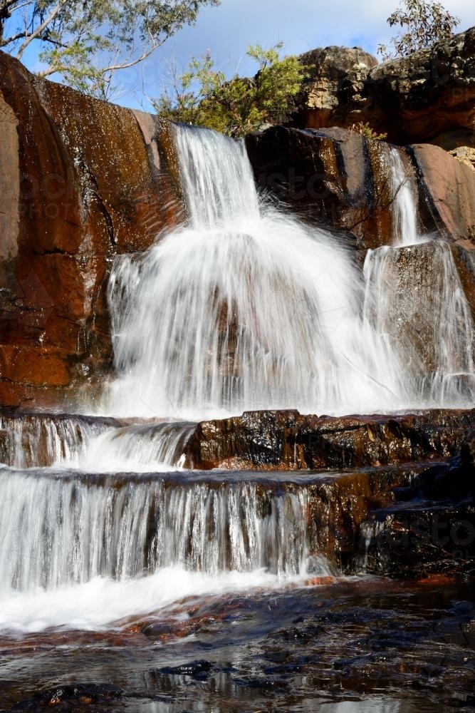 Spectacular tiered waterfall over colourful red sandstone - Australian Stock Image