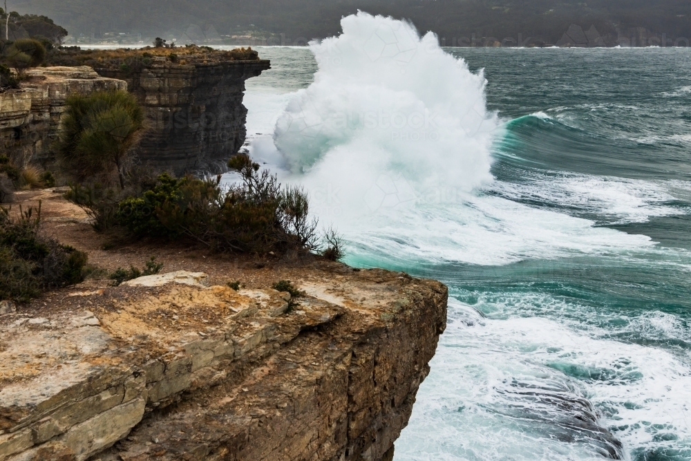 Spectacular waves crashing against cliffs in stormy ocean swell. - Australian Stock Image