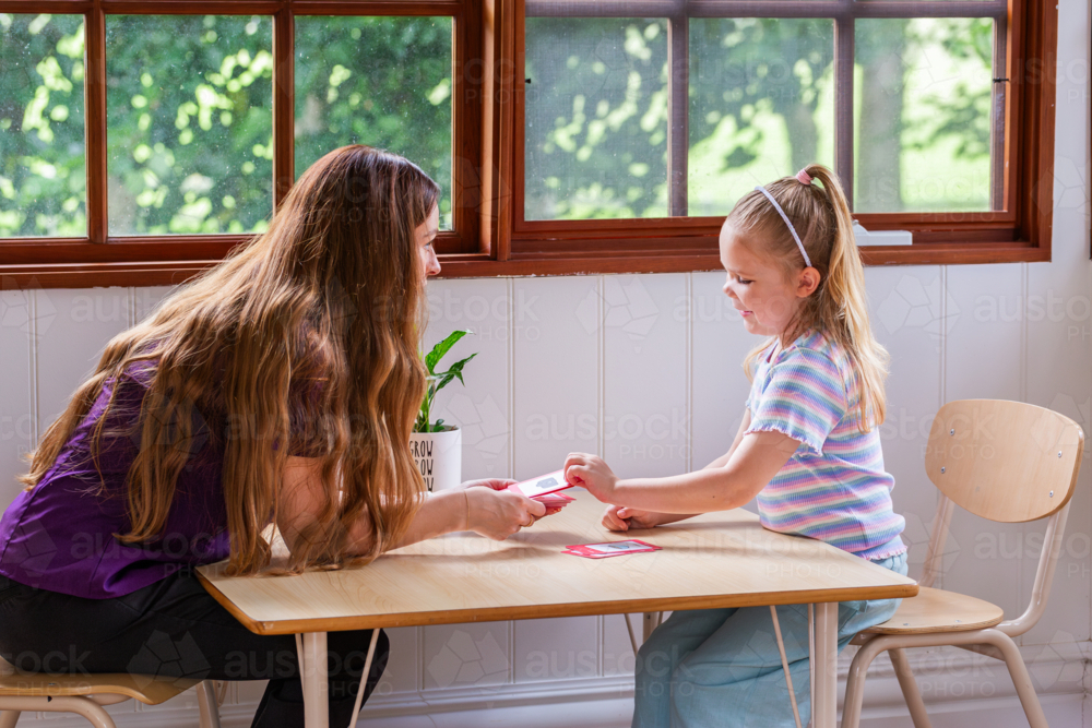 Speech pathologist working with young girl using word flash cards for language development - Australian Stock Image